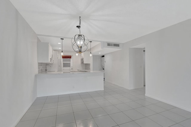 kitchen featuring white cabinets, kitchen peninsula, decorative light fixtures, and light tile patterned flooring