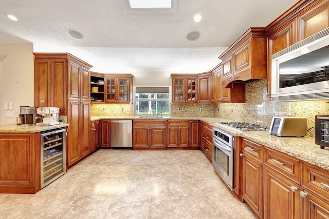 kitchen with wine cooler, light stone countertops, stainless steel appliances, a textured ceiling, and sink