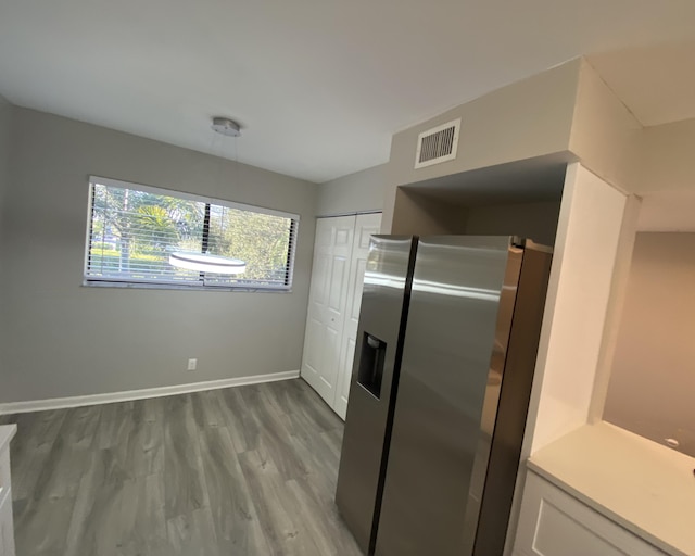 kitchen featuring stainless steel fridge, white cabinetry, and light hardwood / wood-style flooring