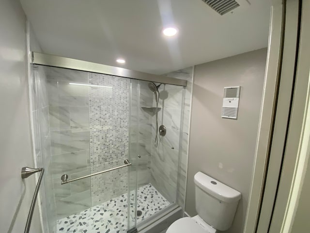 bathroom with a shower with door and toilet