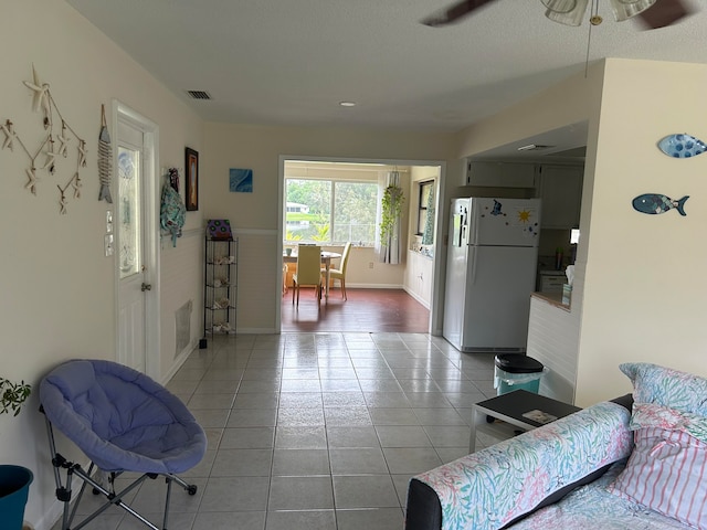 tiled living room featuring ceiling fan and a textured ceiling