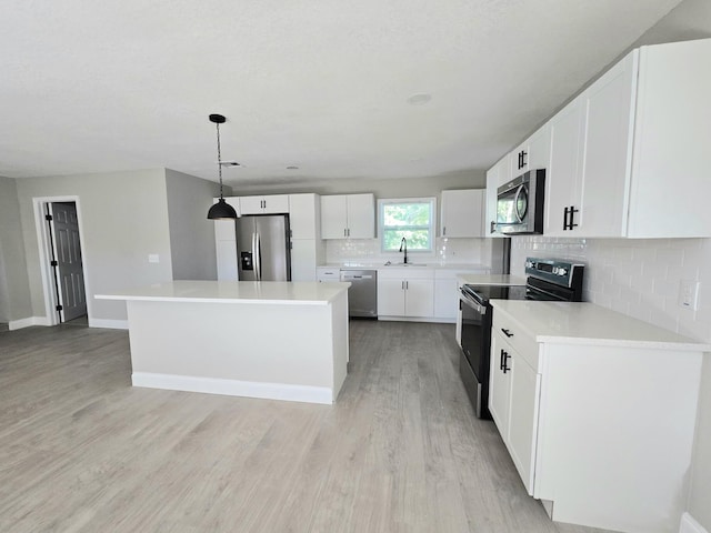 kitchen with pendant lighting, light hardwood / wood-style floors, a center island, white cabinetry, and stainless steel appliances