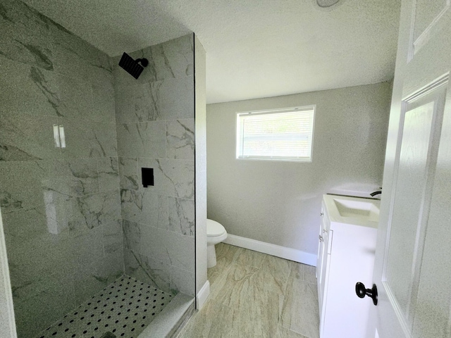 bathroom with tiled shower, vanity, and toilet