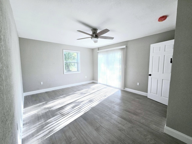 unfurnished room with ceiling fan and dark wood-type flooring