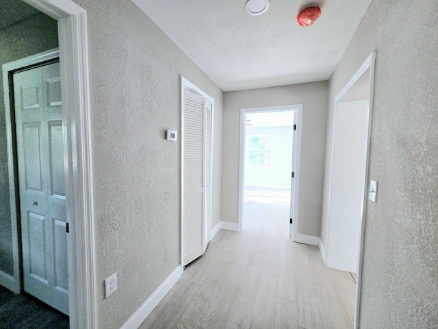 hall featuring light hardwood / wood-style floors and a textured ceiling