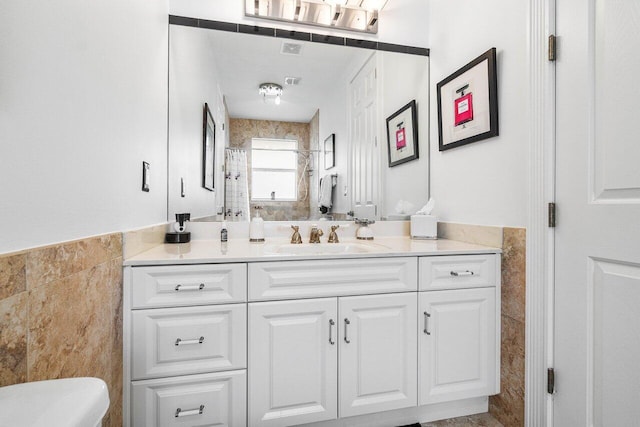 bathroom featuring vanity, toilet, and tile walls