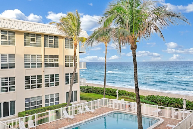 view of swimming pool with a water view and a beach view