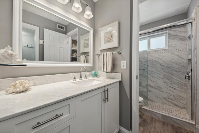 bathroom with a stall shower, visible vents, vanity, and toilet