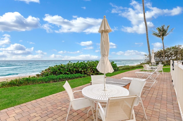 view of patio with a water view, a beach view, and outdoor dining area