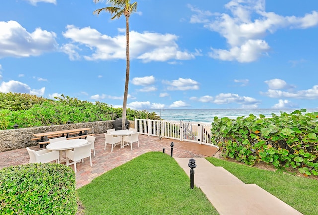 view of yard featuring a patio, a water view, and a beach view