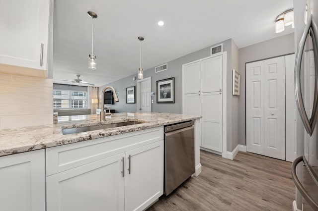 kitchen with appliances with stainless steel finishes, a sink, visible vents, and white cabinetry