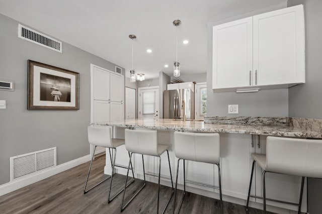 kitchen featuring freestanding refrigerator, visible vents, and white cabinets