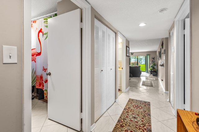 corridor featuring light tile patterned floors and a textured ceiling