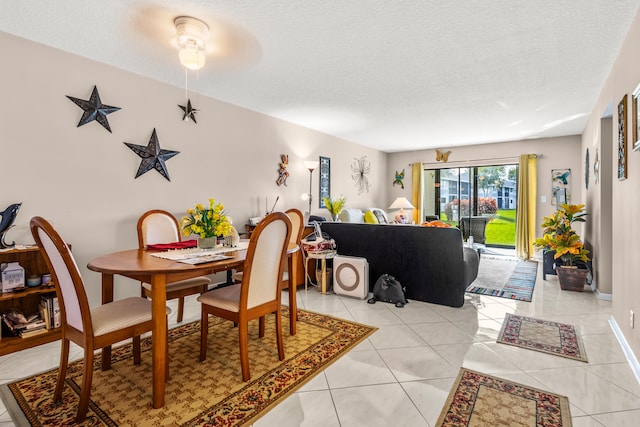 tiled dining space with ceiling fan and a textured ceiling