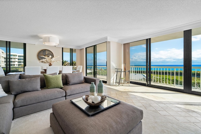 living room with plenty of natural light, a water view, and a wall of windows