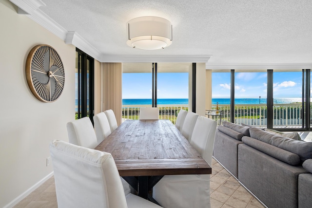 tiled dining room featuring a water view, ornamental molding, a textured ceiling, and a wall of windows