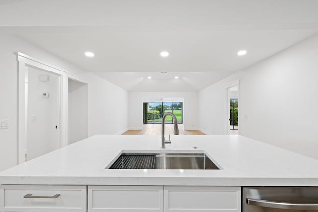 kitchen featuring sink, an island with sink, white cabinets, vaulted ceiling, and stainless steel dishwasher