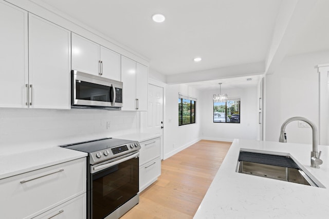 kitchen featuring tasteful backsplash, sink, white cabinets, light hardwood / wood-style flooring, and stainless steel appliances