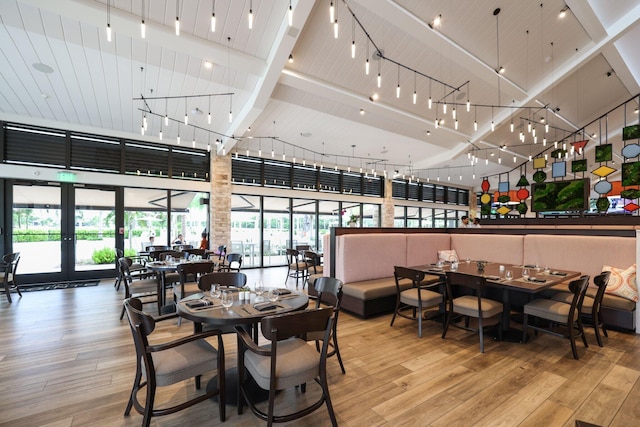 dining area with high vaulted ceiling, light hardwood / wood-style floors, and french doors