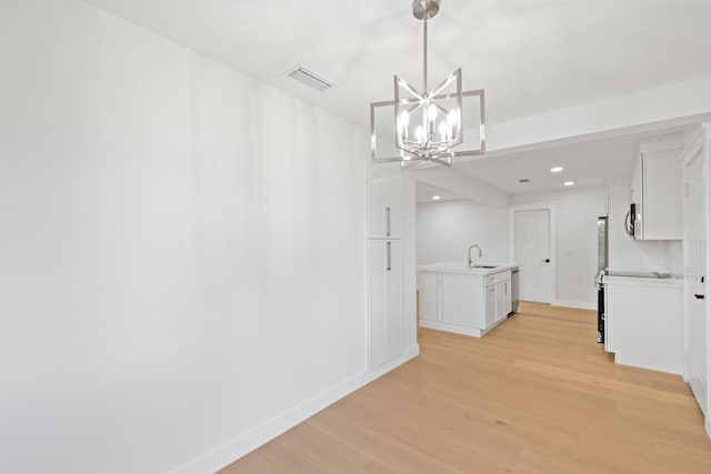 unfurnished dining area with sink, light hardwood / wood-style flooring, and a notable chandelier