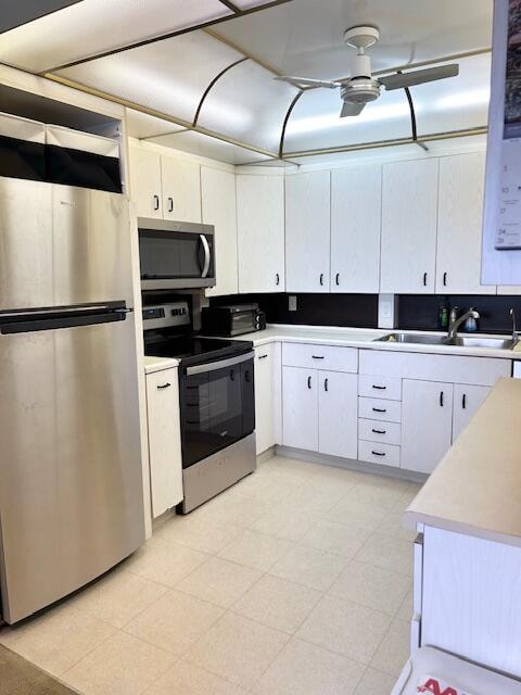 kitchen with ceiling fan, stainless steel appliances, sink, and white cabinetry