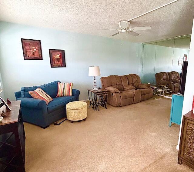 living room featuring carpet, ceiling fan, and a textured ceiling