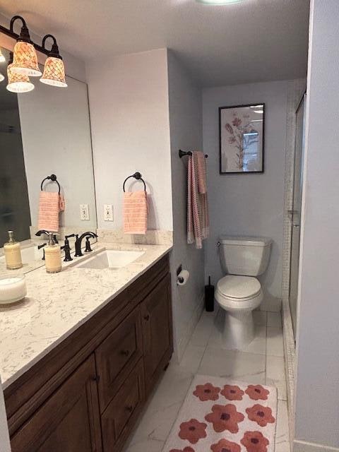 bathroom featuring walk in shower, vanity, and toilet