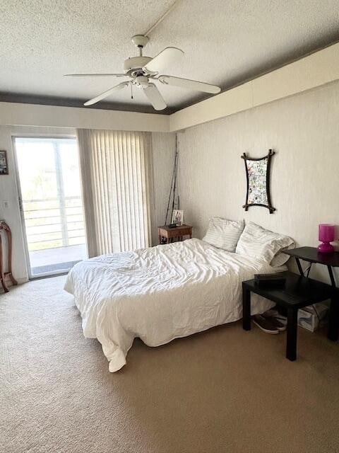 carpeted bedroom with ceiling fan, access to exterior, and a textured ceiling