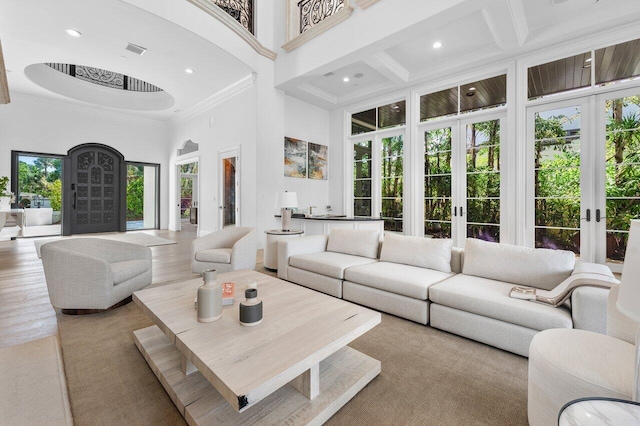 living room with french doors, coffered ceiling, crown molding, beamed ceiling, and a high ceiling