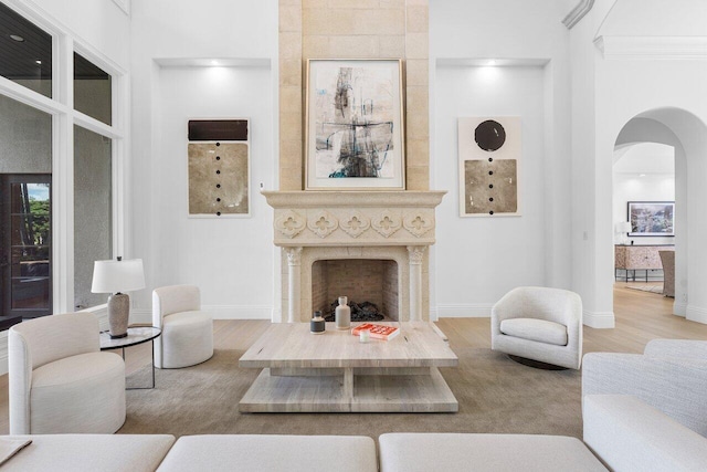 living room with a premium fireplace, a towering ceiling, and light hardwood / wood-style floors