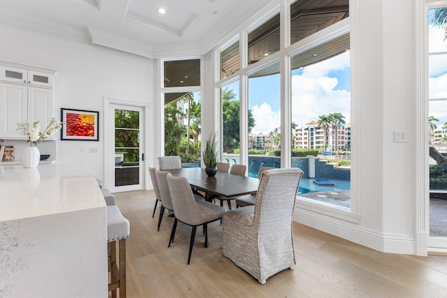 dining room featuring light wood-type flooring, crown molding, and coffered ceiling