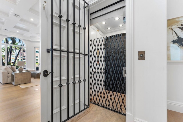 interior space featuring beamed ceiling, ornamental molding, light hardwood / wood-style flooring, and coffered ceiling