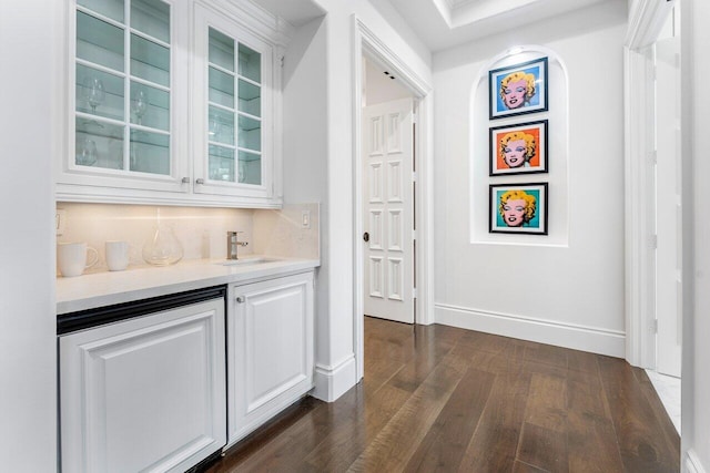 bar featuring dark hardwood / wood-style flooring, white cabinetry, and sink