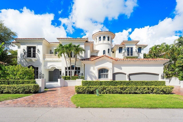 mediterranean / spanish house featuring a front yard, a balcony, and a garage