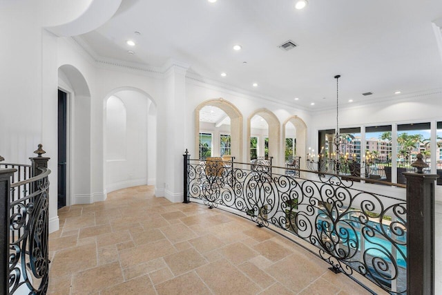 corridor featuring ornamental molding and an inviting chandelier