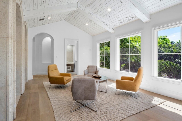 interior space featuring vaulted ceiling with beams, a healthy amount of sunlight, light wood-type flooring, and wood ceiling