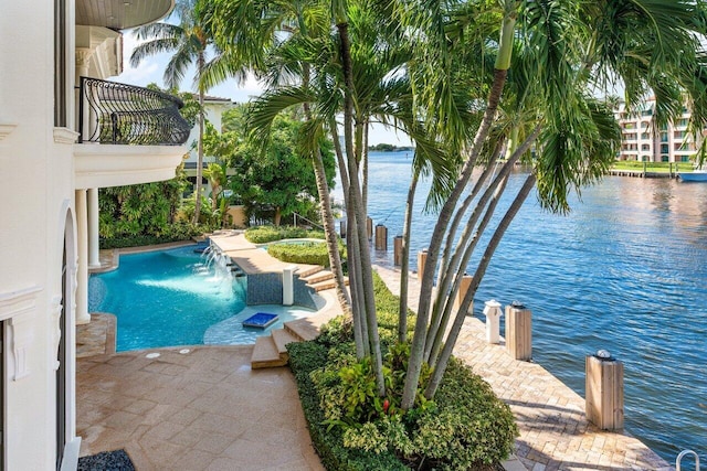 view of pool with pool water feature, a water view, and a hot tub