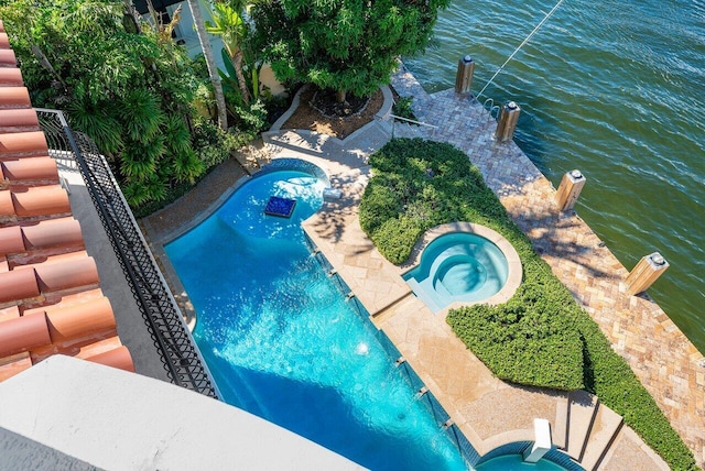 view of pool with pool water feature, a water view, and an in ground hot tub