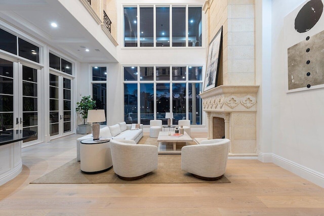 living room featuring a high end fireplace, french doors, a towering ceiling, and wood-type flooring