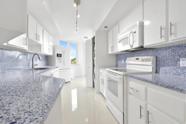 kitchen with backsplash, white appliances, light stone counters, and white cabinets