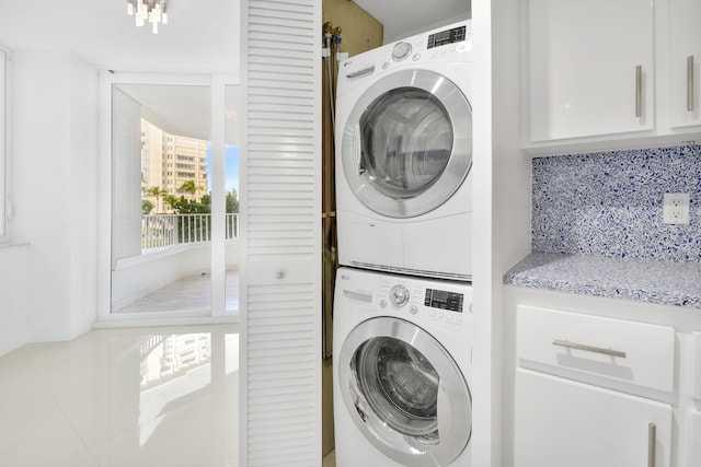 laundry room featuring stacked washing maching and dryer and tile patterned flooring