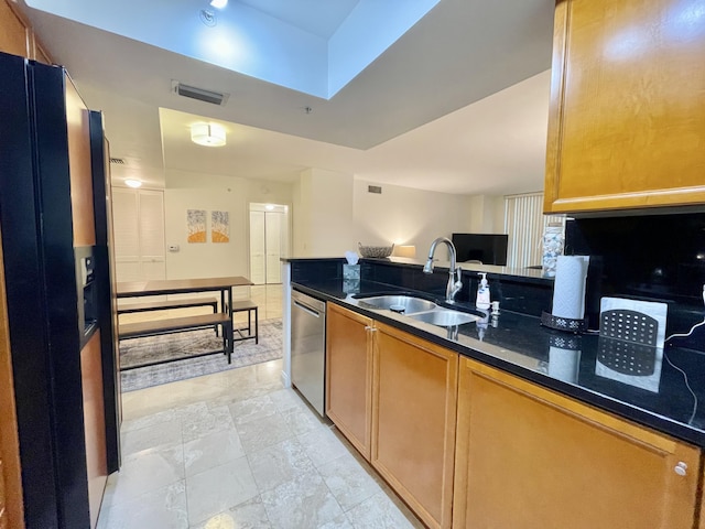 kitchen featuring dishwasher, black fridge with ice dispenser, sink, and dark stone countertops