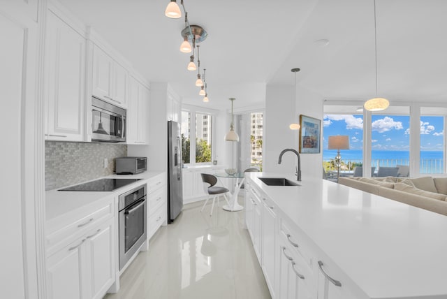 kitchen with decorative light fixtures, appliances with stainless steel finishes, sink, and a wealth of natural light