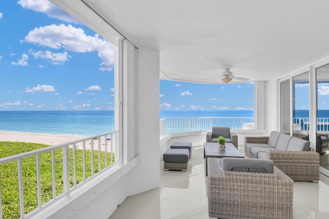 sunroom / solarium featuring ceiling fan, a water view, and a view of the beach