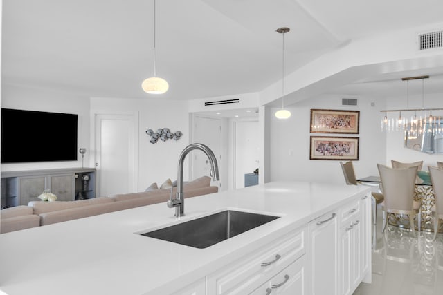 kitchen with white cabinets, sink, a chandelier, and decorative light fixtures