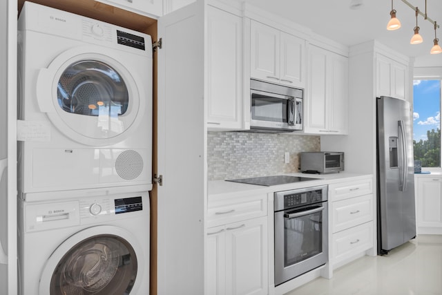 kitchen with pendant lighting, white cabinets, stacked washing maching and dryer, backsplash, and appliances with stainless steel finishes