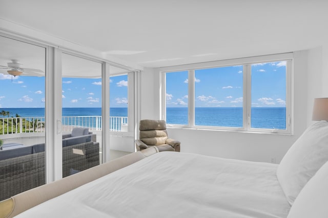 bedroom with a view of the beach, a water view, and access to exterior