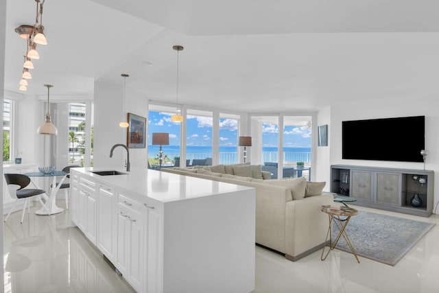 kitchen featuring hanging light fixtures, white cabinetry, sink, and an island with sink