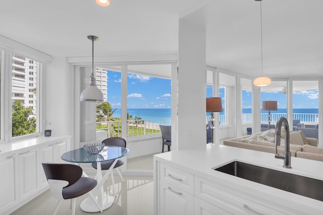 kitchen featuring decorative light fixtures, a water view, sink, and white cabinets