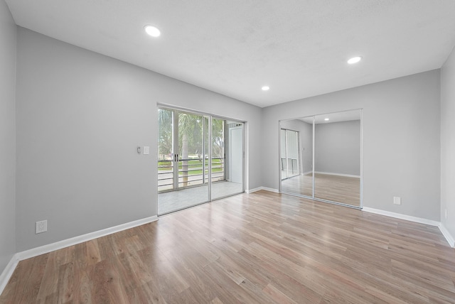 spare room featuring recessed lighting, light wood-style flooring, and baseboards